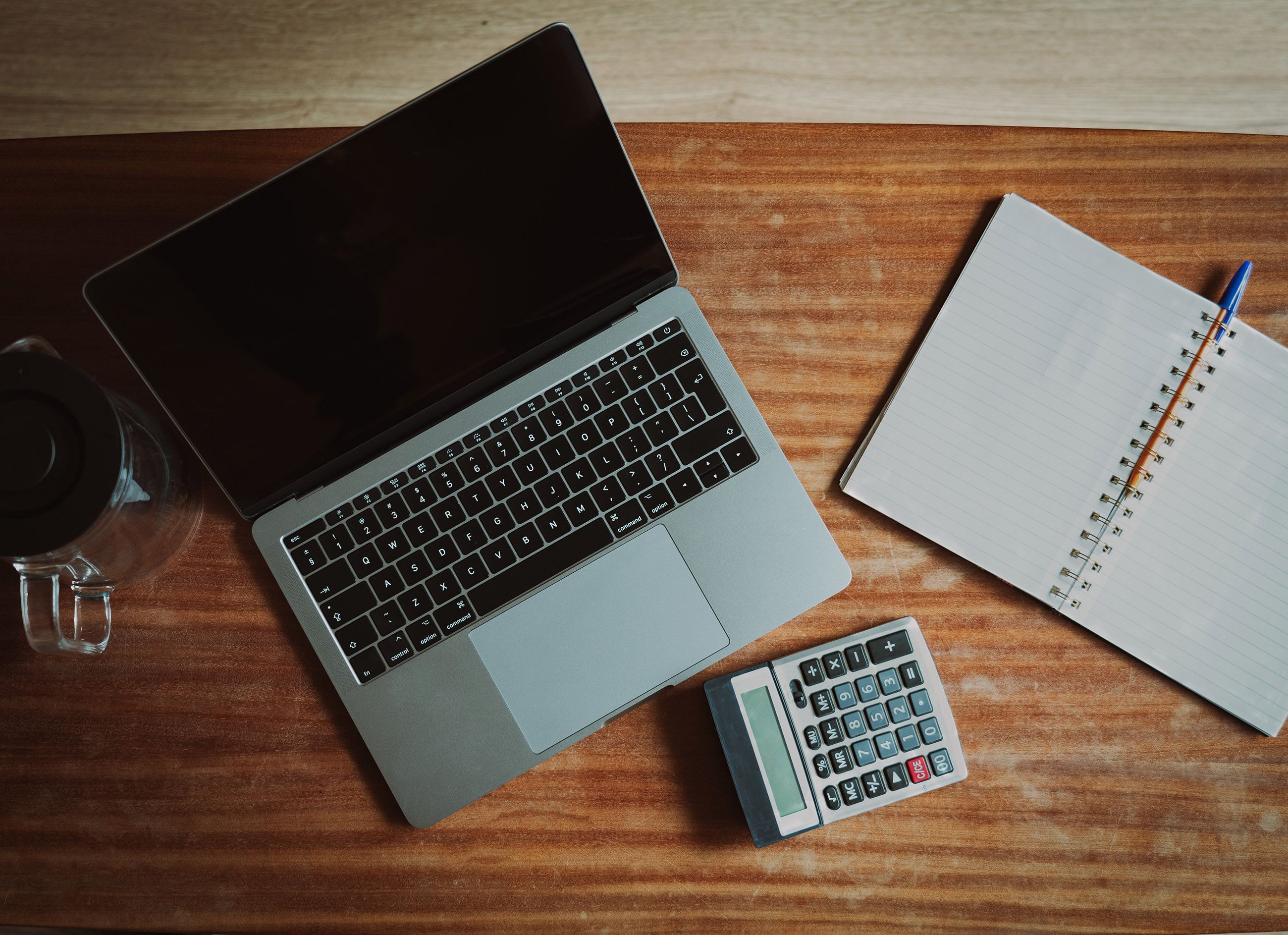 A photographer reviewing financial reports on a laptop with a camera on the desk.